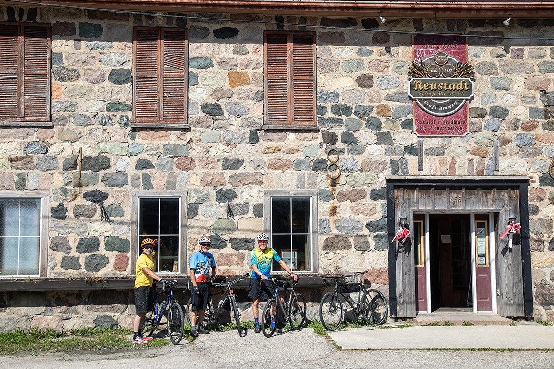 Three cyclists outside an old stone building.