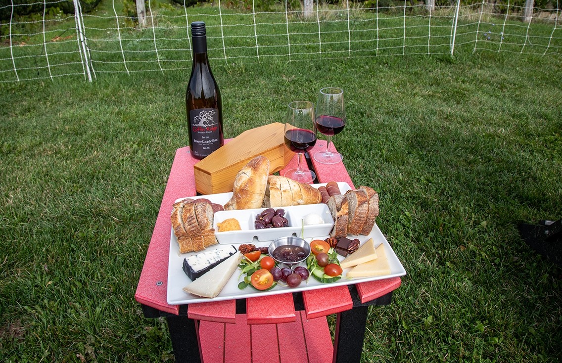 A small red table holds a cheese plate and glasses of wine.