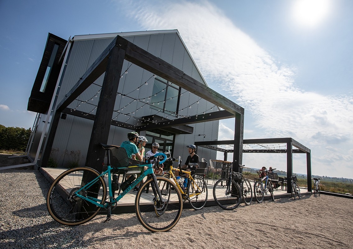 Cyclists seated on an outdoor patio on a bright day.