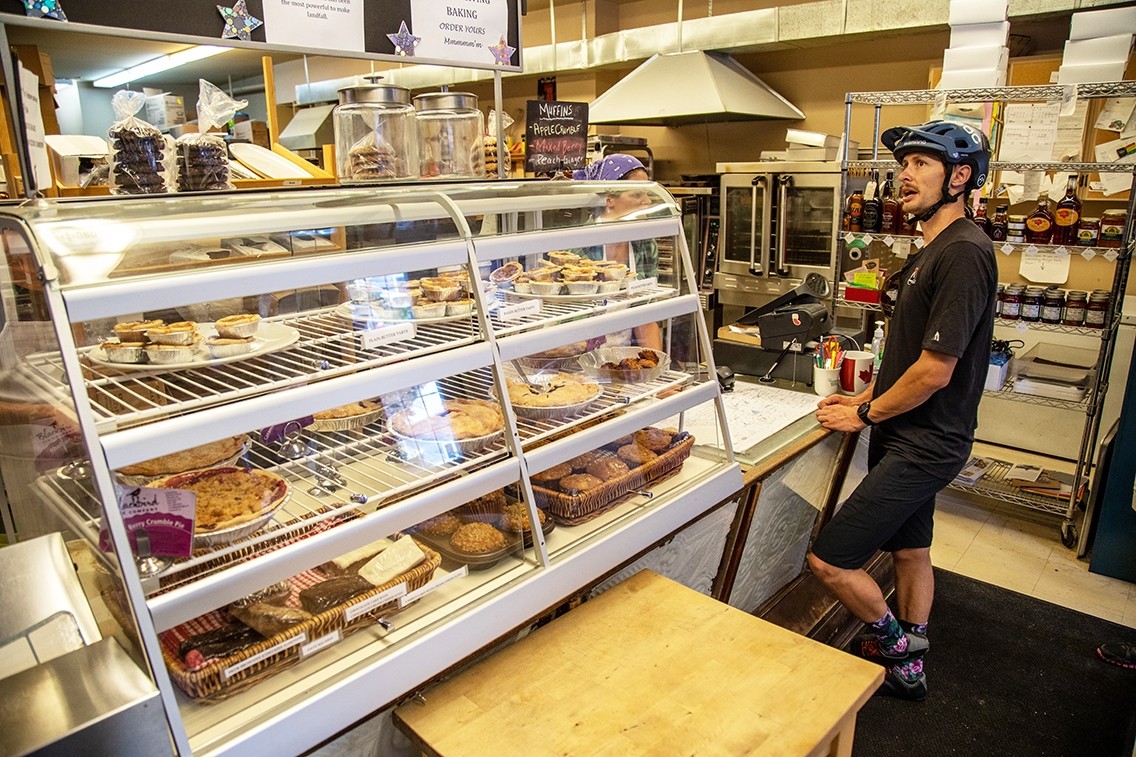 A person wearing a bicycle helmet places an order inside a bakery.