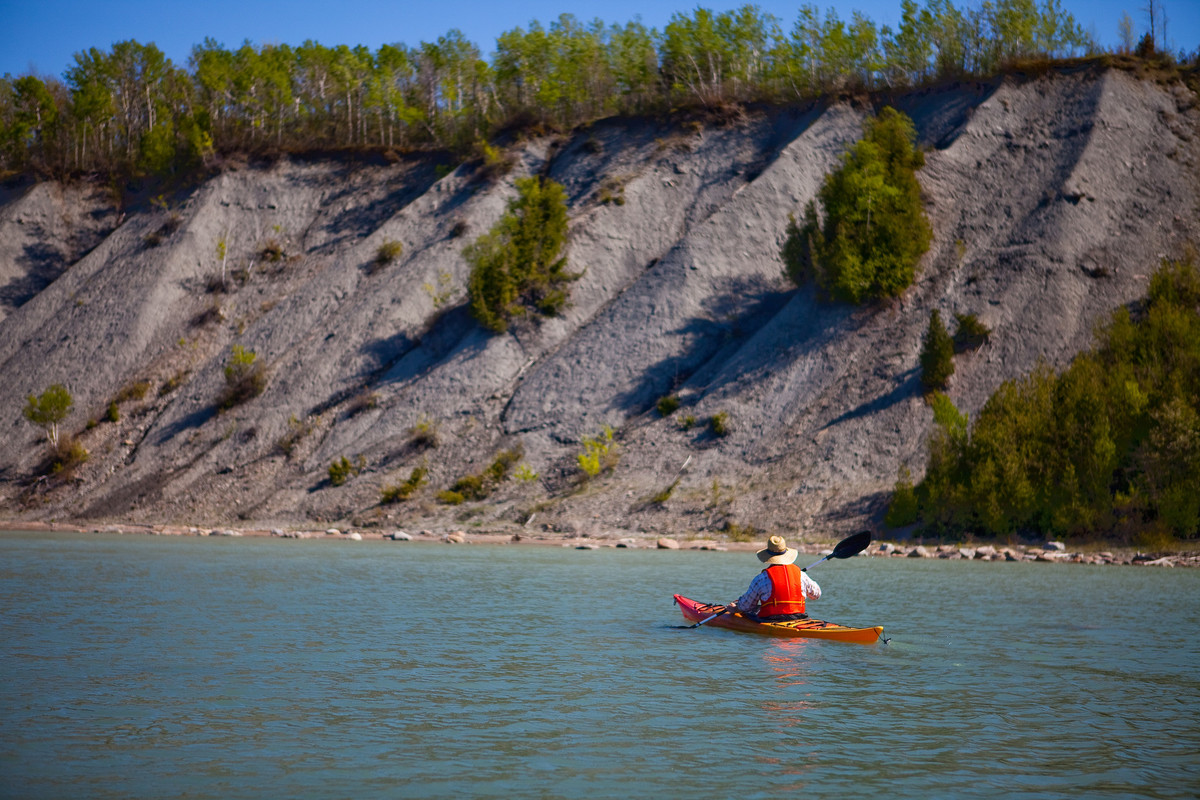 Person Kayaking in river by bluff 