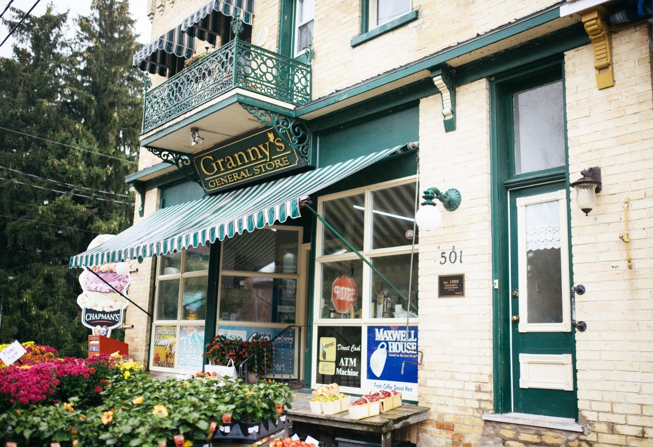 Outside of a brick store painted white with green accents