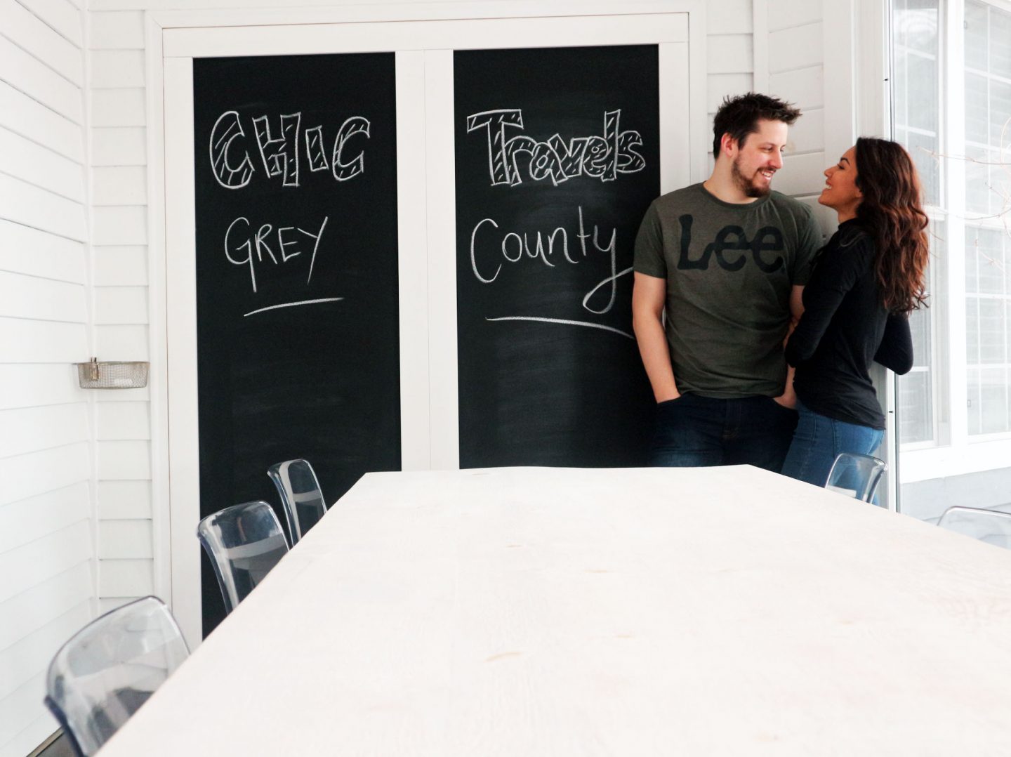 A couple smile into each other's eyes inside a bright white room.