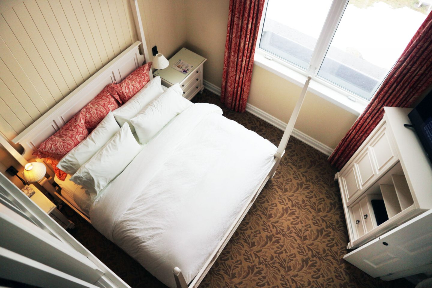 Top down view of a neatly made bed in a guest room.