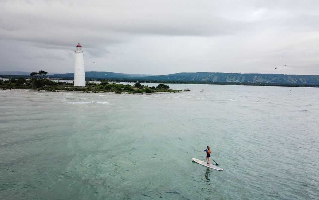 Person on paddle board with lighthouse in the background 