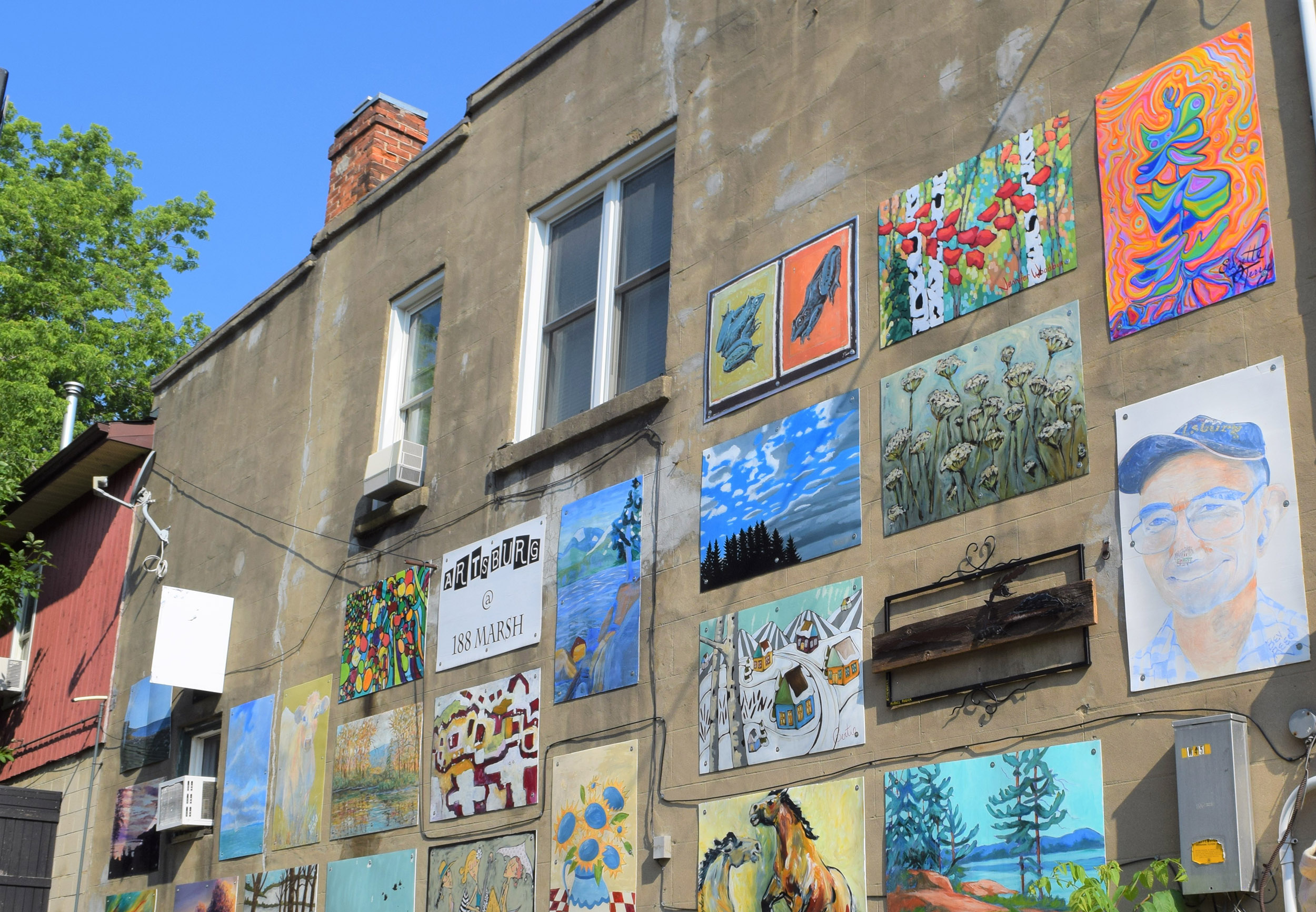 Outdoor wall covered with colorful paintings and murals on the side of a building.
