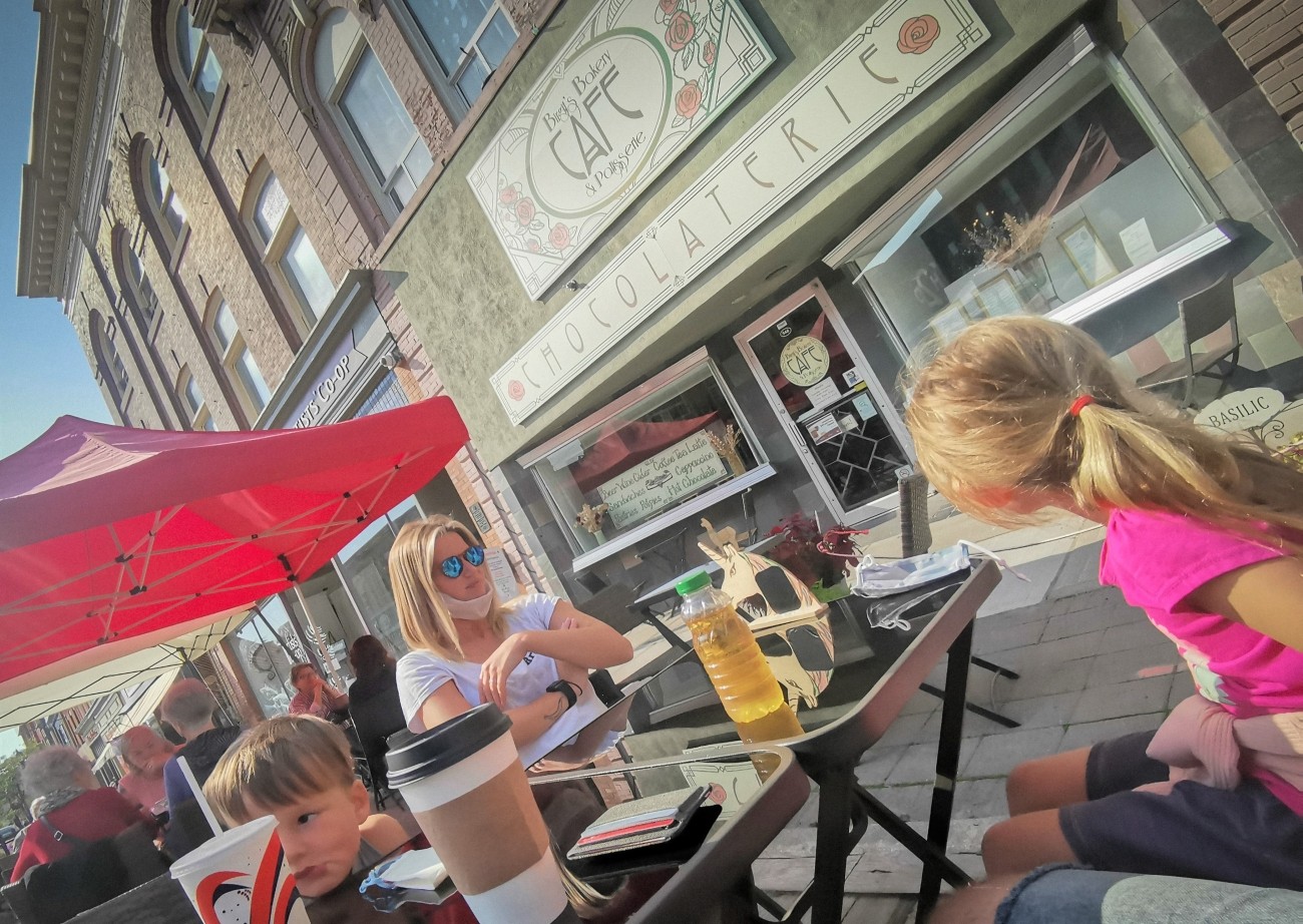 A family seated on outdoor tables in front of a cafe.