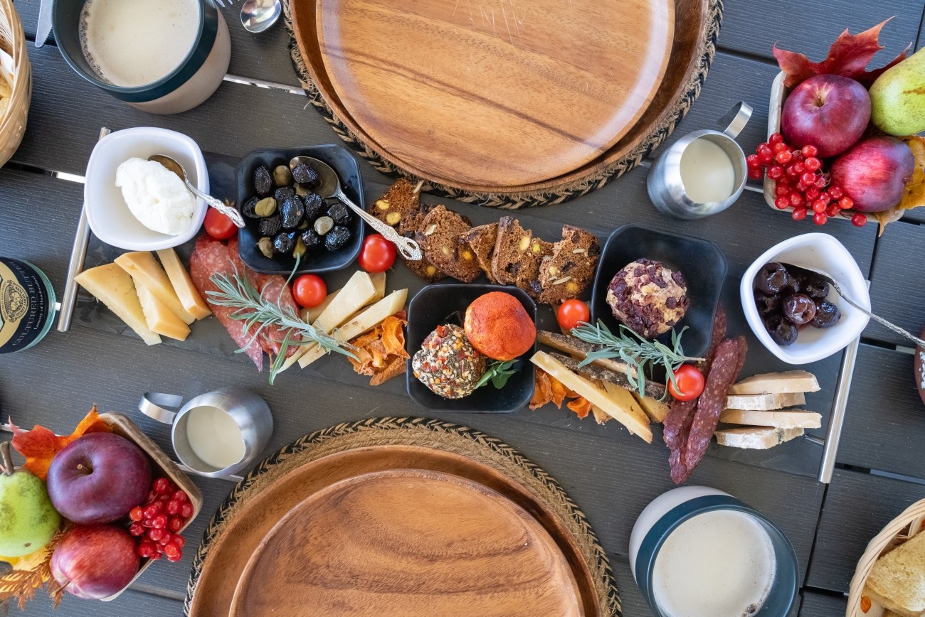 Top down view of a charcuterie board, hot drinks and fruit.