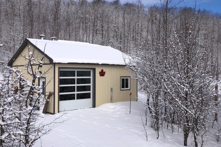 A small building with a garage door on a snowy day.