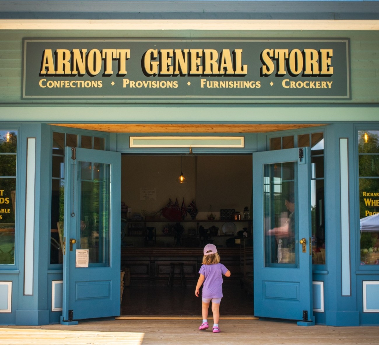 A child walking through open doors at the Arnott General Store.