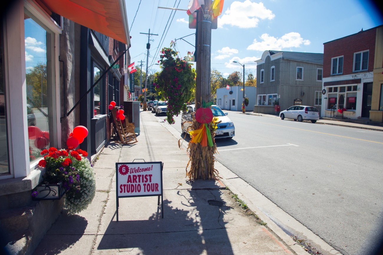 A sidewalk with a sign stating Welcome! Artist Studio Tour