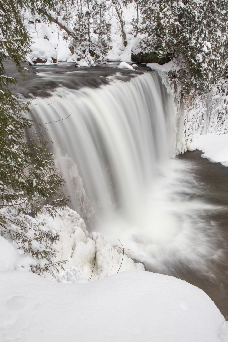 Water cascades down a waterfall in a wintry forest.