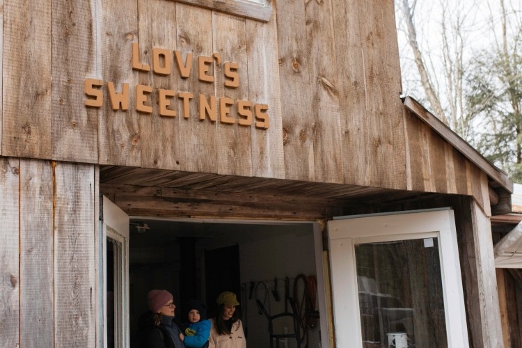 Wooden building with doors open. Sign above doors states "Love's Sweetness".