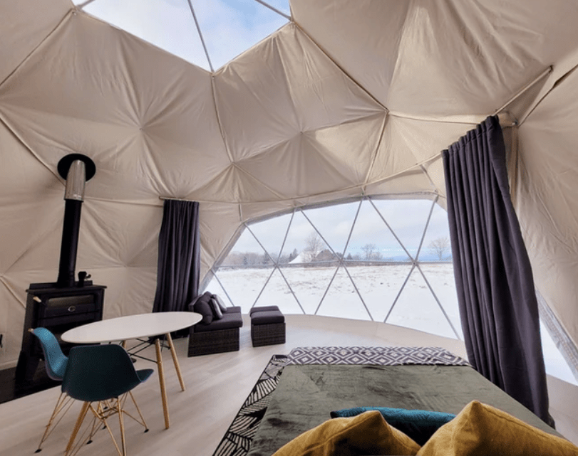 interior of a large dome tent with table, chairs, and fireplace.