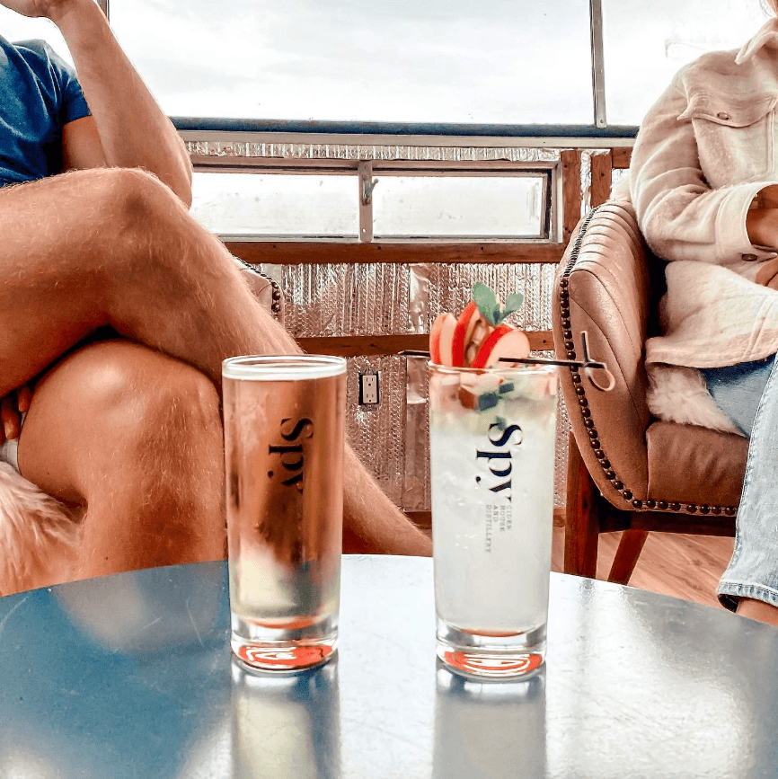 A couple sitting at a table with two glasses of Spy cider