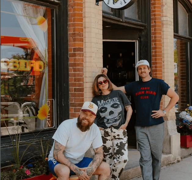 Three people standing in front of a shop
