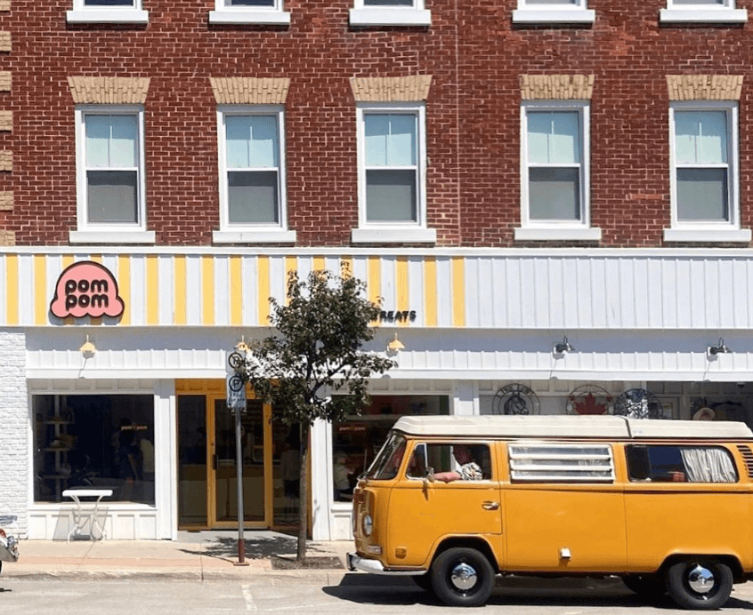 The storefront of Pom Pom Treat Hut with a yellow car out front
