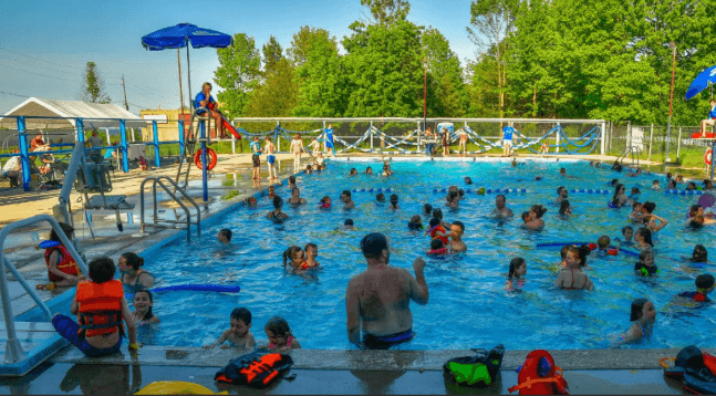 An outdoor pool with many swimmers.