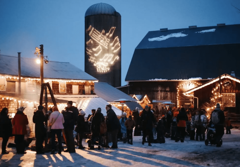 A crowd of attendees enjoy an outdoor Christmas event.
