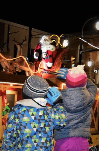 Two children wave at Santa in a parade.