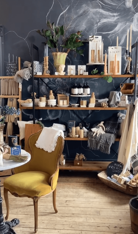 A boutique store shelf with candles, towels and knick-knacks.