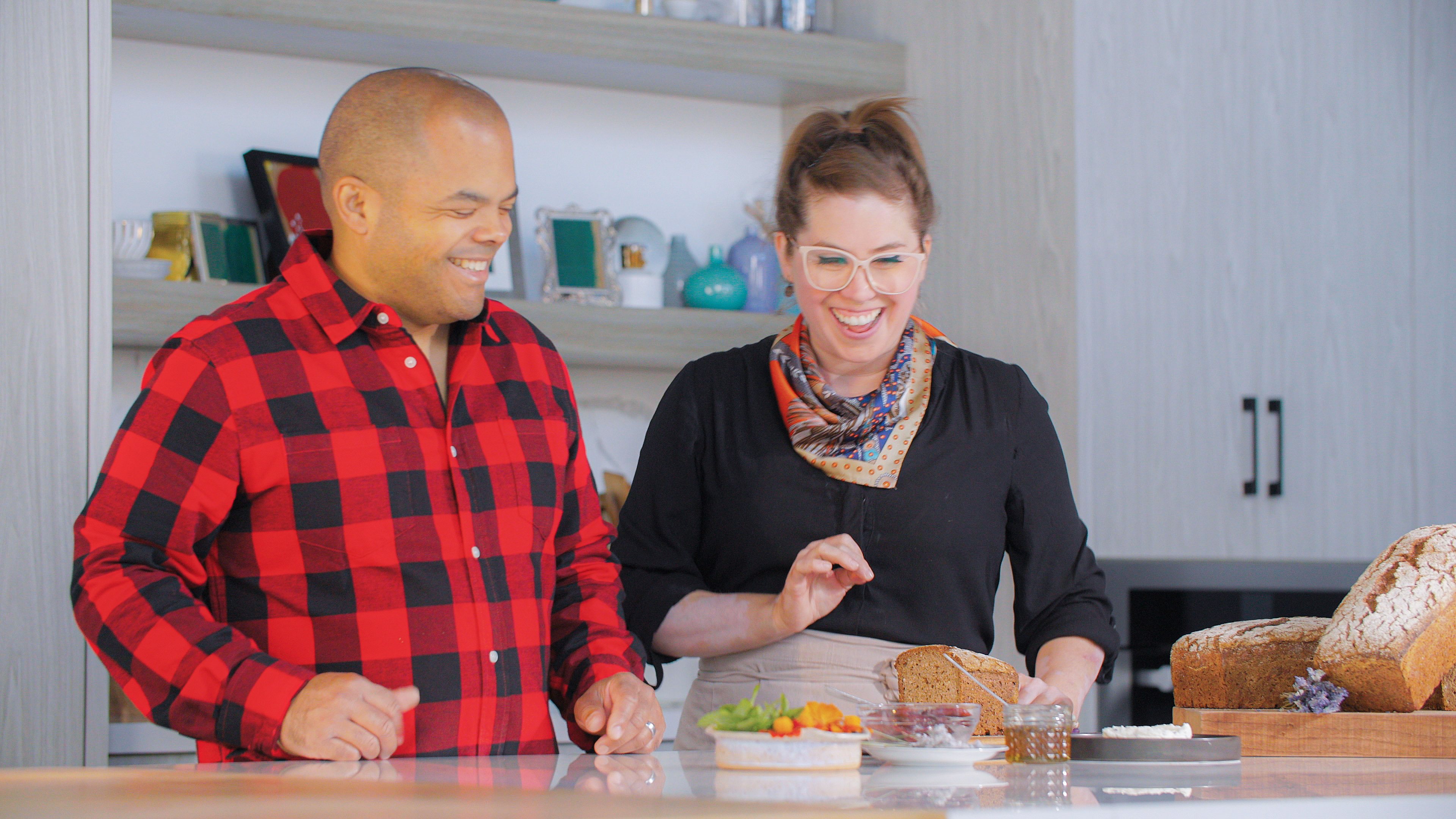 Two smiling people preparing food.