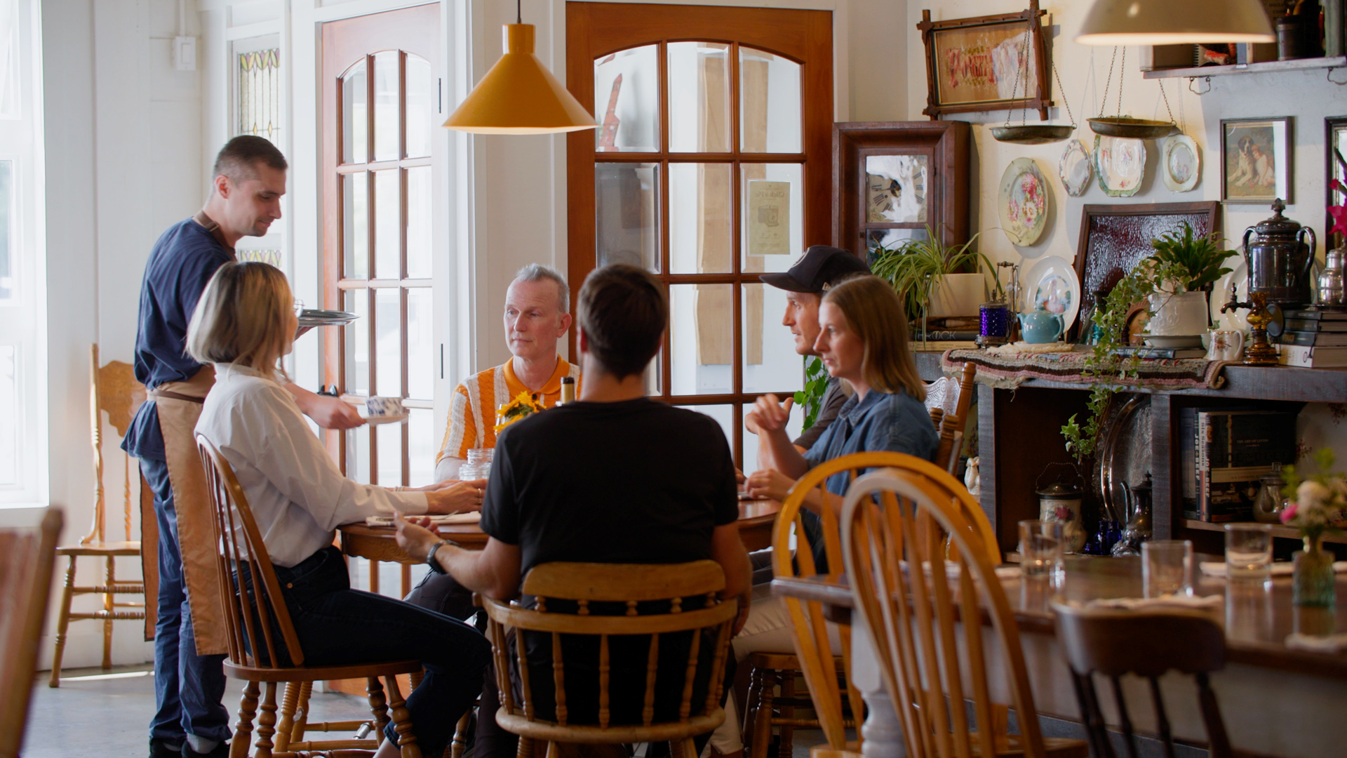 A waiter serves a group of seated diners.