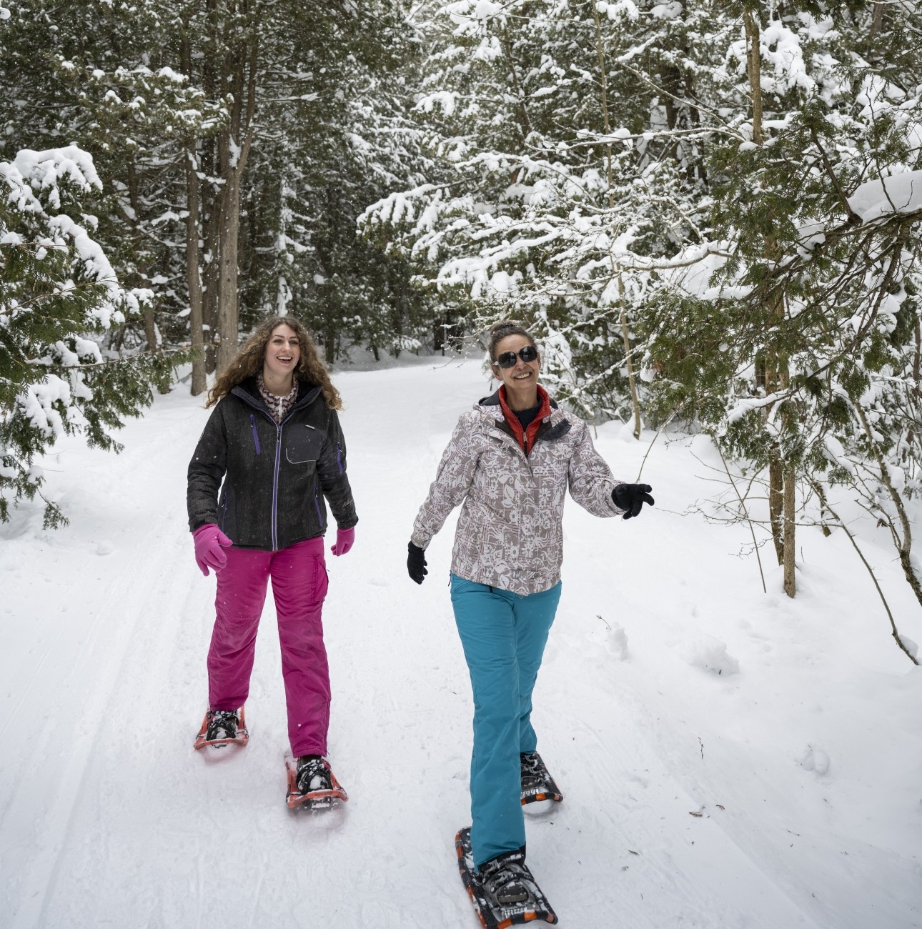 Two women smile while snowshoeing